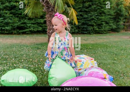 Zwei Jahre altes Baby spielt Ballons auf dem Gras, Sommerparty Stockfoto