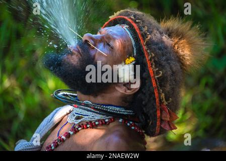 Mitglied des Huli-Stammes, der Wasser spritzt, im Tari-Tal im südlichen Hochland von Papua-Neuguinea. Stockfoto