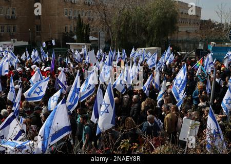 Jerusalem, Israel. 13. Februar 2023. Israelis halten während eines Protests gegen die rechte Regierung außerhalb der Knesset die Flagge. Kredit: Ilia Yefimovich/dpa/Alamy Live News Stockfoto