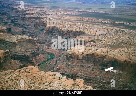 Ein kleines Flugzeug fliegt über dem Colorado River in einer Schlucht im Canyonlands National Park, Utah, USA Stockfoto