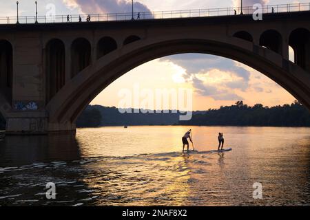 Paddleboarder gleiten auf dem Potomac River unter der Key Bridge in Georgetown; Georgetown, District of Columbia, Vereinigte Staaten von Amerika Stockfoto