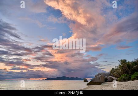 Sonnenuntergang und Wolken über Praslin vom Strand von Anse Source D'Argent, L'Union Estate, La Digue, Seychellen aus gesehen Stockfoto