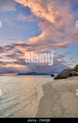 Sonnenuntergang und Wolken über Praslin vom Strand von Anse Source D'Argent, L'Union Estate, La Digue, Seychellen aus gesehen Stockfoto