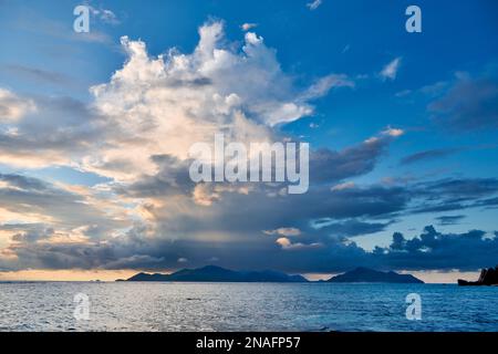 Sonnenuntergang und Wolken über Praslin vom Strand von Anse Source D'Argent, L'Union Estate, La Digue, Seychellen aus gesehen Stockfoto