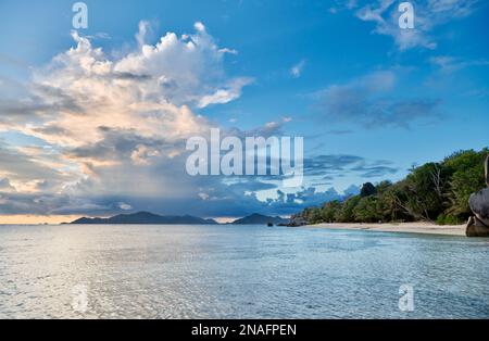 Sonnenuntergang und Wolken über Praslin vom Strand von Anse Source D'Argent, L'Union Estate, La Digue, Seychellen aus gesehen Stockfoto