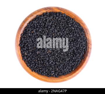 Schwarze Kreuzkümmelsamen in Holzschüssel, isoliert auf weißem Hintergrund. Ein Haufen schwarzer Nigella-Samen. Nigella sativa. Draufsicht Stockfoto