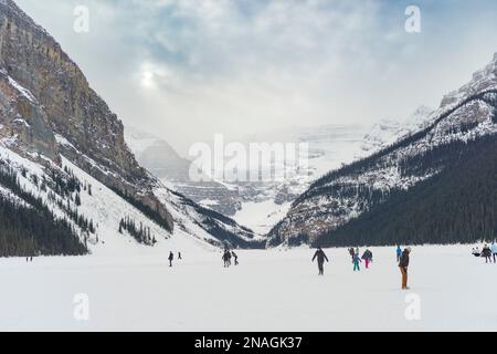 Touristen Schlittschuhlaufen und im Winter einen gefrorenen Lake Louise genießen, Banff National Park, Alberta, Kanada; Improvement District No. 9, Alberta, Kanada Stockfoto