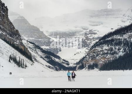 Touristen Schlittschuhlaufen und im Winter einen gefrorenen Lake Louise genießen, Banff National Park, Alberta, Kanada; Improvement District No. 9, Alberta, Kanada Stockfoto