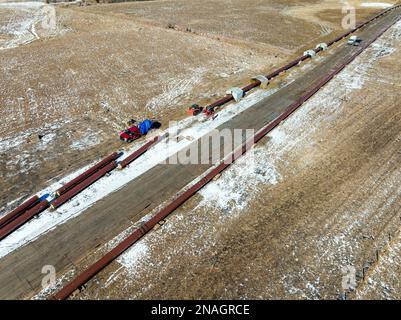 Luftaufnahme des Rohrleitungsbaus auf einem schneebedeckten Feld westlich von Calgary in Alberta, Kanada Stockfoto