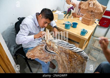 Ein Kunsthandwerker beginnt in einer Werkstatt in San Martin Tilcajete, Oaxaca, Mexiko, ein Geistertier der Alebrije zu malen. Stockfoto