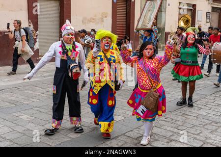 Eine Parade von Clowns auf der Macedonio Alcala Fußgängerstraße im historischen Zentrum von Oaxaca, Mexiko zur Weihnachtszeit. Stockfoto