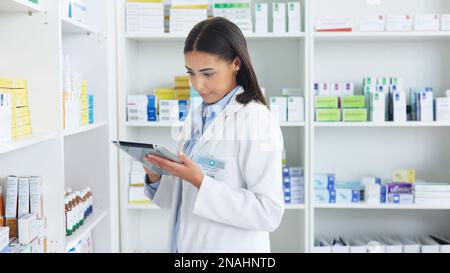 Eine junge Apothekerin, die in einer Apotheke mit einer Tablette vorrätig ist. Arzt, der Rezepte und Medikamente in Klinik oder Apotheke vorbereitet. Gesundheitswesen Stockfoto