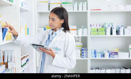 Eine junge Apothekerin, die in einer Apotheke mit einer Tablette vorrätig ist. Arzt, der Rezepte und Medikamente in Klinik oder Apotheke vorbereitet. Gesundheitswesen Stockfoto