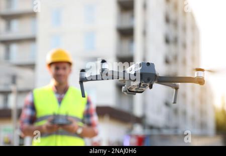 Bauarbeiter, die Drohne mit Fernsteuerung auf der Baustelle bedienen. Luftaufnahmen Stockfoto