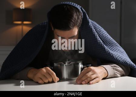 Ein Mann mit Karomuster inhaliert über dem Saucetopf im Haus Stockfoto