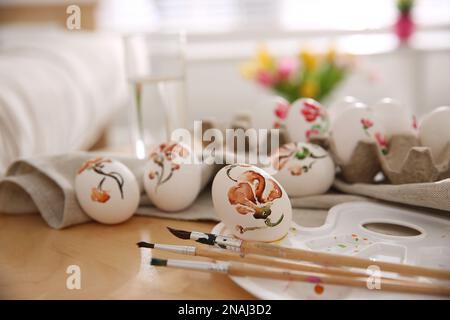 Wunderschön bemalte Ostereier und Bürsten auf Holztisch im Haus Stockfoto