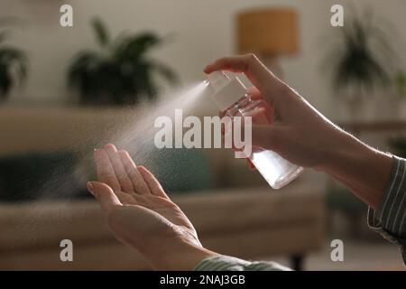 Eine Frau, die in geschlossenen Räumen Antiseptikum auf die Hand spritzt, Nahaufnahme Stockfoto