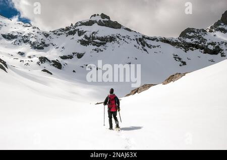 Schneewanderer auf einem schneebedeckten Hügel an einem bewölkten Tag in den Bergen Picos de Europa, Spanien Stockfoto