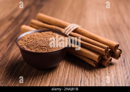 Zimtpulver und Stöcken auf Holztisch Stockfoto