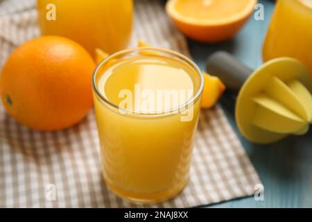 Frisch zubereiteter Saft, Orangen und Reibahle auf blauem Holztisch, Nahaufnahme Stockfoto