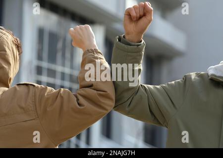 Die Leute grüßen sich gegenseitig, indem sie Ellbogen statt Handschlag im Freien anstoßen, Nahaufnahme Stockfoto