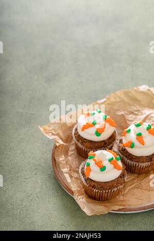 Karotten-Cupcakes mit Frischkäse-Zuckerguss, dekoriert mit winzigen Karotten, Osterdessert-Idee Stockfoto