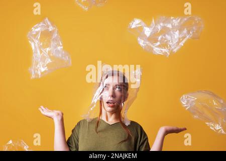 Junge Frau überwältigt von Plastikmüll und erstickt von Plastik Tasche über den Kopf - Ökologie und Umweltverschmutzung Konzept Stockfoto