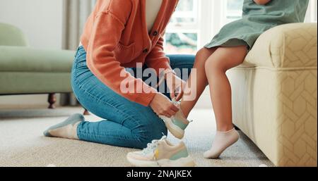 Mutter, Kind und Schuhe zur Vorbereitung auf Schule, Lernen oder Bildung im Schlafzimmer zu Hause. Mom hilft dem kleinen Mädchen mit den Schuhen, die sich vorbereiten Stockfoto