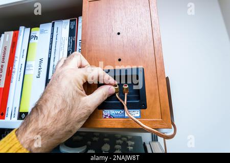 Paris, Frankreich - 13. Dezember 2022: POV männliche Hand verbindet den Tannoy Mercury V1-Lautsprecher neben mehreren Designbüchern Stockfoto