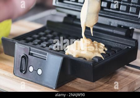 Nahaufnahme des Teigs in Waffeleisen, Zubereitung von hausgemachten belgischen Waffeln Stockfoto