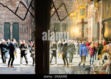 Straßburg, Frankreich - 20. März 2015: Touristenmassen Fußgänger in der Nähe der Kathedrale Notre Dame de Strasbourg Haupteingangsfassade spiegelt sich in Souvenirläden wider Stockfoto