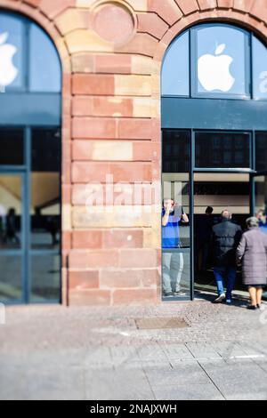 Straßburg, Frankreich - 20. März 2015: Apple Genius Arbeiter, der den Himmel betrachtet und die Sonnenfinsternis bewundert, während Kunden den Computerladen betreten - Neigeobjektiv Stockfoto