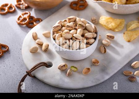Auswahl an salzigen Snacks auf dem Tisch mit Brezeln, Pistazien und Kartoffelchips, Snacks, die gut zu Bier passen Stockfoto