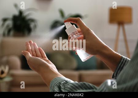 Eine Frau, die in geschlossenen Räumen Antiseptikum auf die Hand spritzt, Nahaufnahme Stockfoto