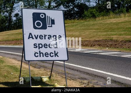 Ein Straßenschild informiert Fahrer, dass sie in einen Abschnitt der Autobahn einfahren, auf dem Kameras zur Überprüfung der Durchschnittsgeschwindigkeit eingeschaltet sind. Fahren Sie daher nicht mit zu hoher Geschwindigkeit. Stockfoto