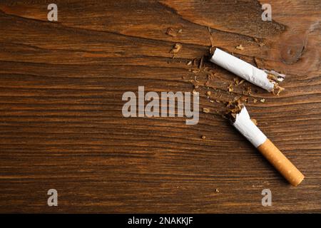 Gebrochene Zigarette auf Holztisch, flach liegend mit Platz für Text. Raucherentwöhnungskonzept Stockfoto