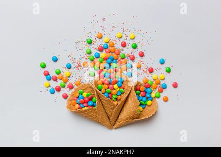 Waffelkonus voller traditioneller Süßigkeiten, die auf farbigen Hintergrund fallen, mit Platz für Kopien. Frohes Weihnachtsangebot. Stockfoto