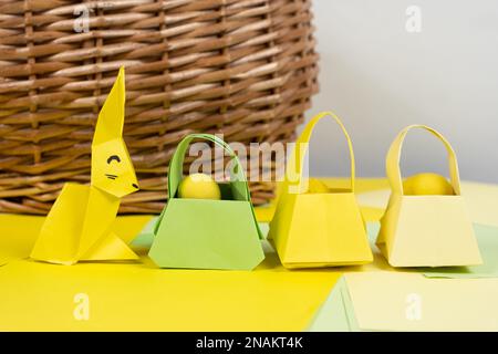 Eine osterhäschen-Figur aus Papier, Origami, und ein Körbchen mit Eiern, Frohe Ostern. Stockfoto