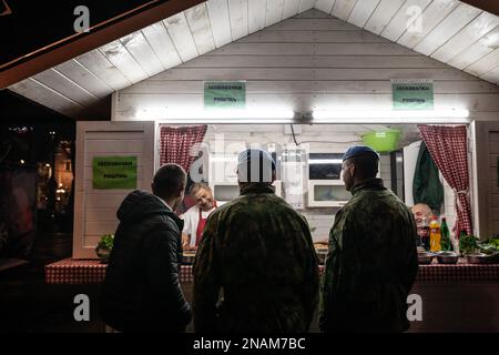 Bild eines Rostilj-Stands mit Soldaten, die nachts in Belgrad, Serbien, auf ihr Essen warten. Ein Rostilj ist ein Fast-Food-Stand, spezialisiert auf gegrillte Me Stockfoto