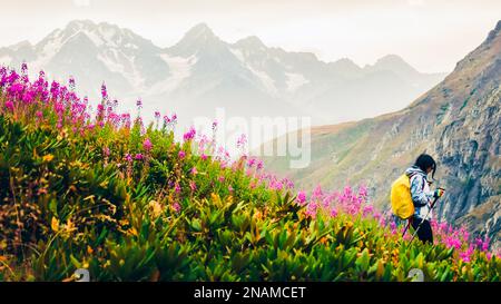 Wanderweibchen mit nordic Walk Pols wandern bergab in grünen kaukasus Bergen Wanderweg im Frühling Natur regnerischen Tag.Freizeitaktivitäten und Gesundheit Stockfoto