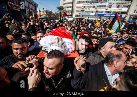 Nablus, Palästina. 13. Februar 2023. (ANMERKUNG DER HERAUSGEBER: Bild zeigt den Tod)die Trauernden tragen den Körper des 22-jährigen Palästinensers Amir al-Bistami, der von der israelischen Armee während eines Überfalls auf die Stadt Nablus im besetzten Westjordanland erschossen wurde. Die israelische Armee sagte, dass ihre Streitkräfte Nablus stürmten und es geschafft hätten, die beiden gesuchten Männer, Osama al-Taweel und Abdel Kamal Jouri, zu verhaften, die beschuldigt werden, vor vier Monaten einen israelischen Soldaten an einem Kontrollpunkt westlich von Nablus getötet zu haben. Kredit: SOPA Images Limited/Alamy Live News Stockfoto