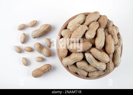 Schüssel voll mit geschälten und gerösteten geschälten Erdnüssen auf weißem Hintergrund, geschlossen Stockfoto