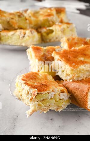 Gericht mit Hühnchen und Kartoffelkuchen auf hellem Hintergrund. Eine Portion hausgemachter Kuchen auf einem weißen Teller auf einem hellen Tisch Stockfoto