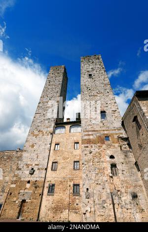 Türme und Häuser auf der Piazza delle Erbe, mittelalterliche Stadt San Gimignano, UNESCO-Weltkulturerbe, Provinz Siena, Toskana, Italien. Stockfoto