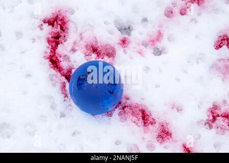Der Begriff der Symbolik. Kristallkugel auf Schnee mit Blutflecken, selektiver Fokus Stockfoto