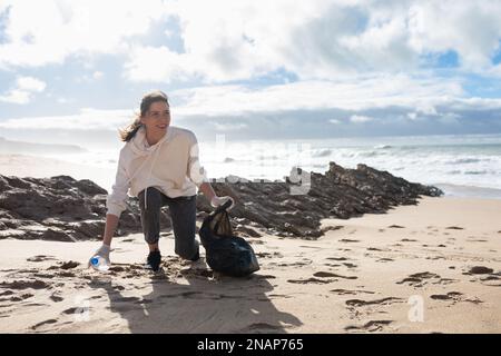 Weibliche Öko-Freiwillige sammeln Plastikmüll am Strand, sammeln Müll, schützen den Planeten, freien Platz Stockfoto