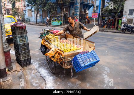 Verkäufer von frischem Obst am Straßenrand, der Bananen und Äpfel aus einem dreirädrigen Karren in Fariapukur, Shyam Bazar, einem Vorort von Kalkutta, Westbengalen, Indien, verkauft Stockfoto