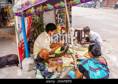 Einheimischer Straßenhalter entfernt Waagen, die Fisch für den Verkauf an einem typischen Straßenstand in Fariapukur, Shyam Bazar, Kalkutta, Westbengalen, Indien vorbereiten Stockfoto