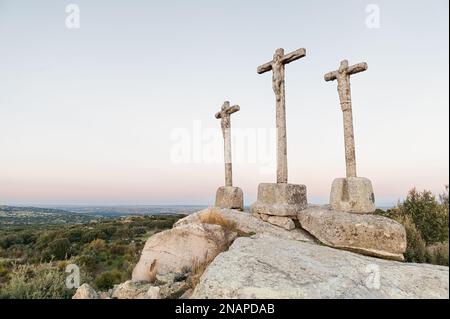 Drei Kreuze aus geschnitztem Stein auf Granitfelsen in der Dämmerung des Himmels Stockfoto