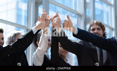 Daumen hoch von einem zufriedenen Business-Team, das sich über den Erfolg freut, den es bei der Arbeit gemeinsam erzielt. Vielfältige Gruppe von Mitarbeitern, die sich auf den Erfolg freuen und Stockfoto